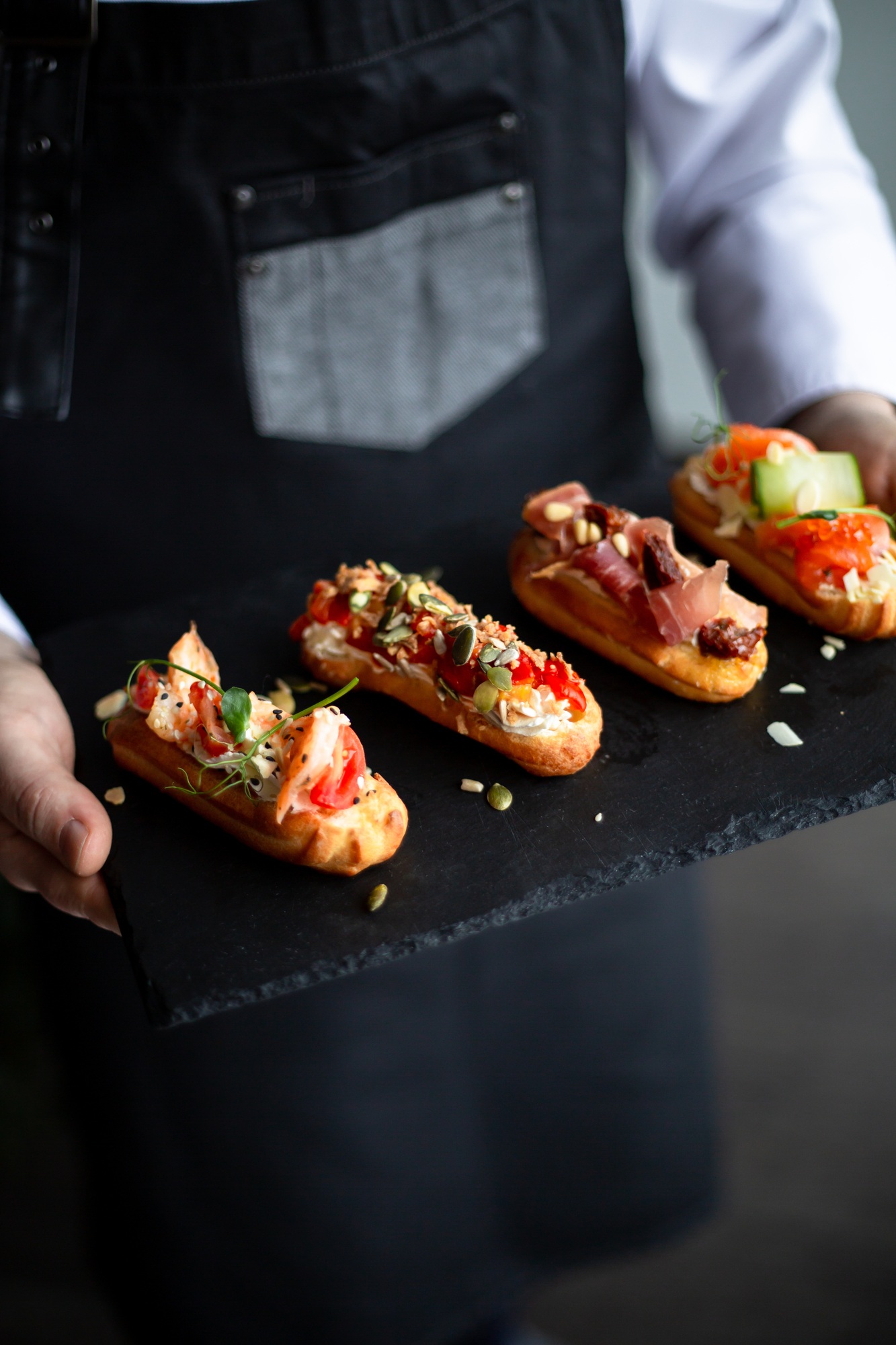 Eclairs with salmon, fresh vegetables and herbs, gourmet snacks, catering for a festive table.