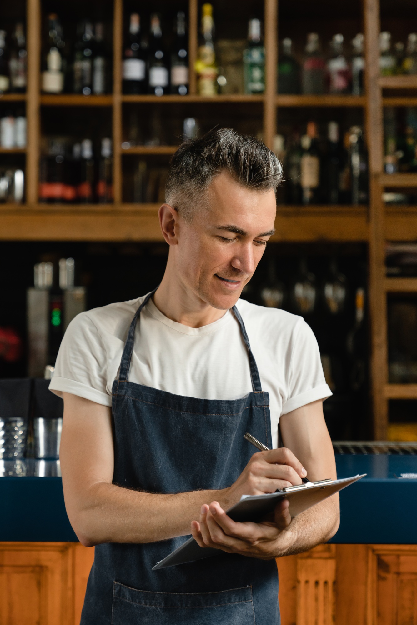 Mature cafe owner restaurant waiter standing close to bar counter checking quality.Small business